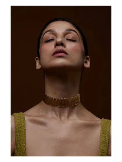 A serene and artistic shot focusing on the choker. The closed eyes and soft lighting create a mood of quiet luxury and elegance.