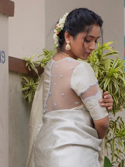 The back design of this blouse is the main highlight. The sheer net with scattered motifs gives a graceful and sophisticated look, perfect for pairing with elegant silk or tissue sarees for special occasions.
