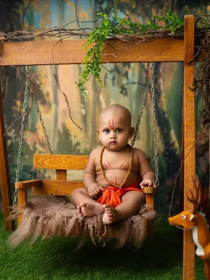 A baby dressed as a young Swami Samarth devotee, sitting peacefully on a swing in a forest setting. These spiritual themes create a sense of calm and reverence.