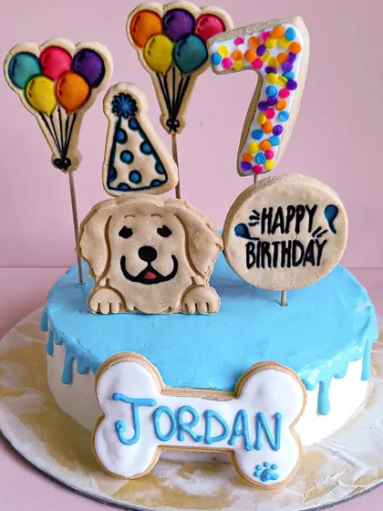 Jordan's 7th birthday cake in a cool blue. The design includes a party hat cookie, a colorful number 7, and a personalized name bone.