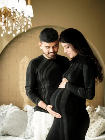 A classic portrait of the couple, both gently holding the baby bump, symbolizing their shared journey into parenting again.