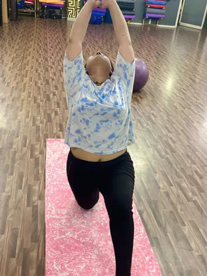 A member fully engaged in the crescent lunge, reaching upwards to lengthen the spine. This is a powerful pose for building lower body strength.