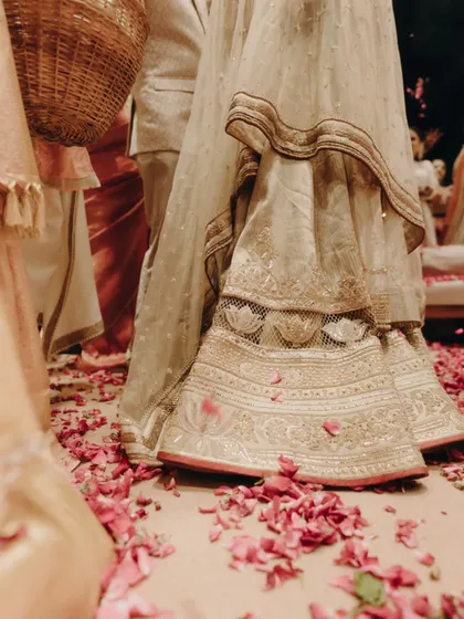 The bride's lehenga skirt, with its beautiful lotus embroidery, trailing over a carpet of rose petals.