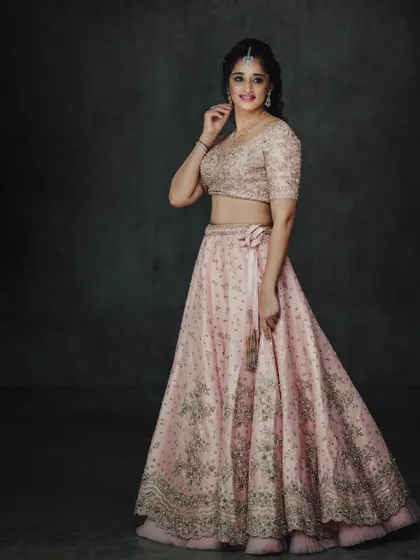 A classic studio portrait that gives a complete view of this elegant pink lehenga. The dark backdrop ensures the delicate embroidery and color stand out.