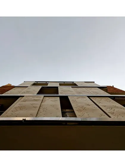 A view looking up at the facade, showing how the perforated screens create a dynamic and functional exterior. These shading devices are crucial for managing heat gain from the sun, which is a core principle of energy-efficient building design.