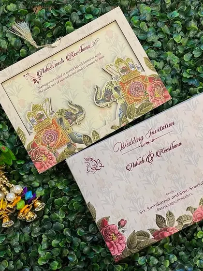 This beautiful invitation features a die-cut frame with elephant motifs. The design combines floral patterns with traditional elements for a unique look.