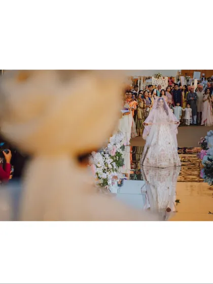 A creative shot of the bride's entrance, viewed from the groom's perspective, with her reflection in the mirrored aisle.