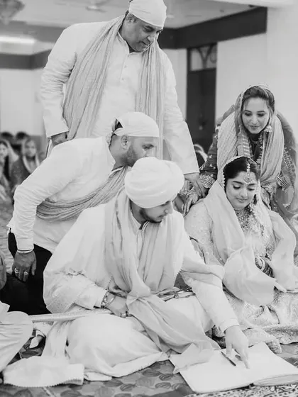 The signing of the marriage register during the Anand Karaj. This is a quiet, official moment amidst the spiritual ceremony, and I capture it candidly.