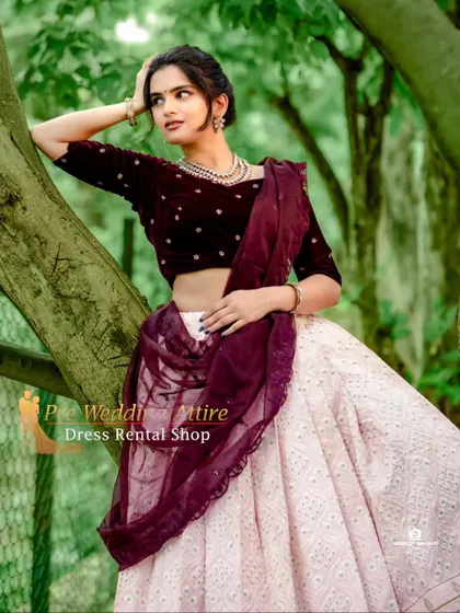 A model posing in a tree, showcasing the modern crop top and skirt set. The maroon velvet top contrasts beautifully with the light, airy skirt.
