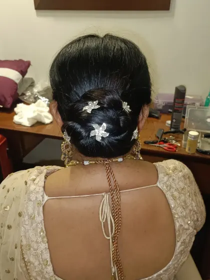 A clean and polished low bun, accessorized with delicate, flower-shaped crystal pins. This minimalist yet elegant style is ideal for a reception or for a bride who prefers subtle details.