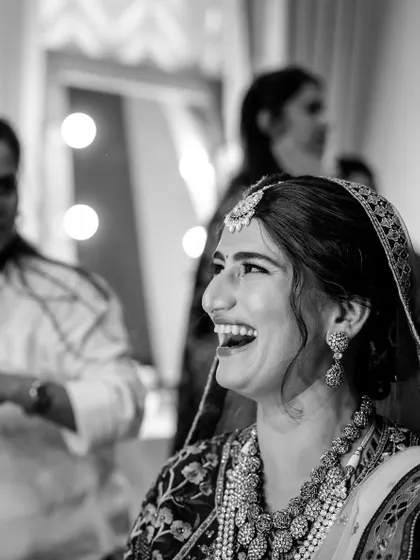 A joyful black and white portrait of Sneha, capturing her beautiful smile as she finalizes her wedding look. Her happiness is the best accessory.