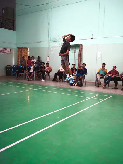 A full-court view of a player executing a jump smash during a game, with spectators watching. Our training prepares players for real tournament environments.