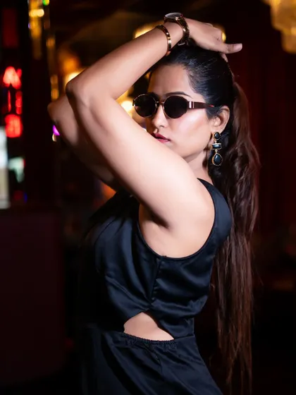 A dynamic lifestyle shot for a fashion influencer in a dimly lit club. The pose is strong and confident, perfect for a post about evening wear or a night out.