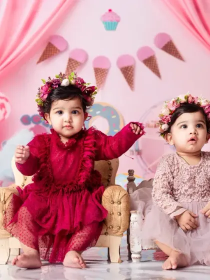 Two little sweethearts sitting on their thrones in our vibrant Candy Land themed first birthday setup.