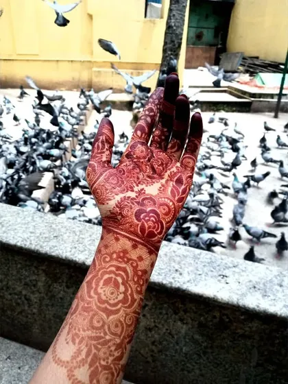 A dynamic shot of the henna stain against a backdrop of flying pigeons, capturing a moment of beauty.