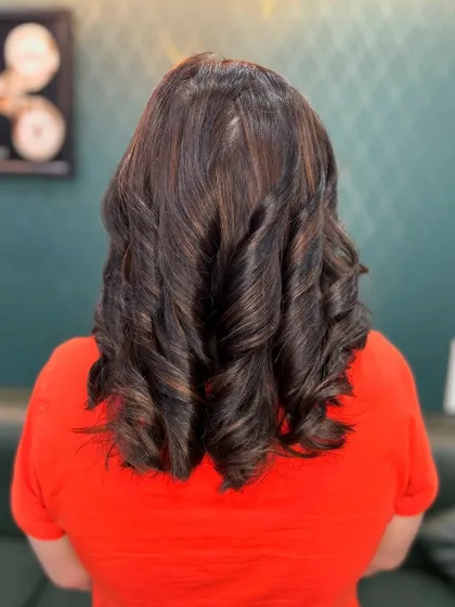 Natural brown hues styled into tight curls. This look enhances the hair's natural texture while adding a beautiful, dimensional glow.