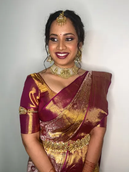 A happy bride showcasing her complete traditional look. The makeup, jewelry, and saree all work together to create a vision of timeless elegance.