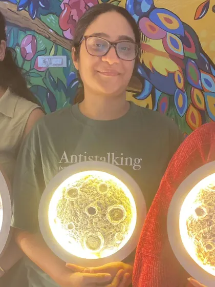 A young artist with her finished moon lamp, a perfect example of the creative fun we offer for all ages.