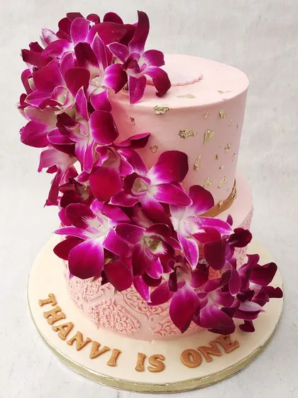 We make a bold and beautiful statement with this two-tiered orchid cake. A dramatic cascade of fresh, deep magenta orchids flows down the side of the soft pink tiers, creating a stunning visual contrast that is both luxurious and exotic.