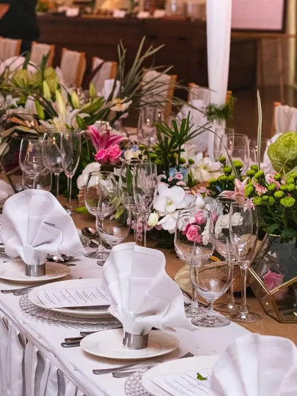 A fresh and modern tablescape with white linens and arrangements of lilies and tropical greens. This crisp, clean look is perfect for a daytime event or a contemporary celebration.