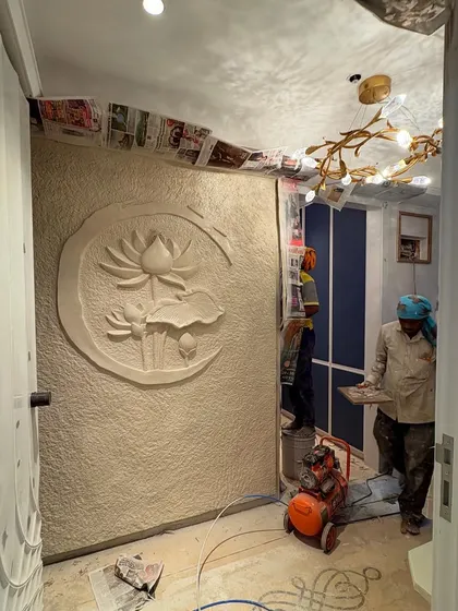 A behind-the-scenes shot of the lotus mural installation in progress. This view shows the scale of the work and the equipment used to create the final textured wall effect.