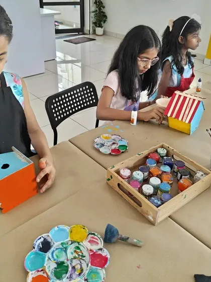 A group of girls focused on their birdhouse painting project. It's a great activity that combines painting with a bit of simple construction.