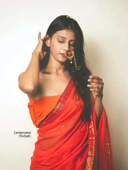 A soft and sensual portrait, with the model's hair partially covering her face as she adjusts her nath.