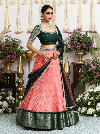 The full, standing view of the coral and green lehenga, a perfect outfit for a summer wedding.