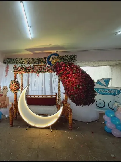 The same outdoor baby shower setup with the moon prop lit up, creating a focal point for the decoration.