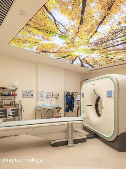 This diagnostic room for a PET-CT scanner uses a backlit ceiling showing a canopy of autumn trees. This "positive distraction" is a key patient-centered design strategy to reduce anxiety during medical procedures.