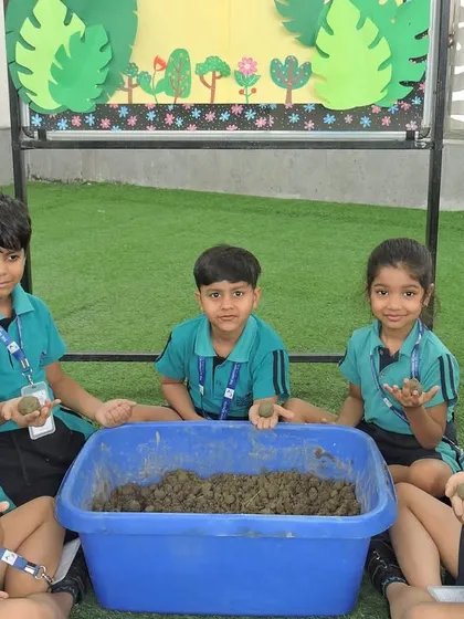A group of students proudly holds up the seed balls they made, learning about germination and environmental responsibility.