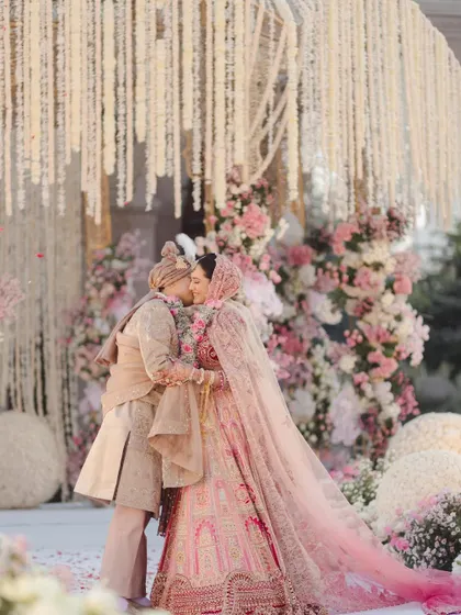 A kiss amidst a floral wonderland. This shot is the epitome of romance, with the couple framed by their stunning wedding decor.
