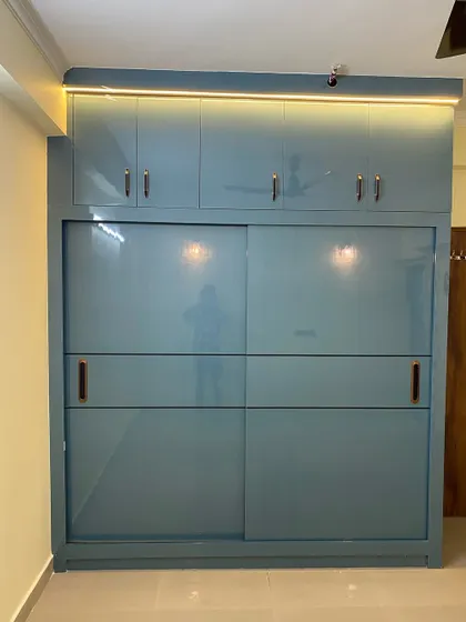 A large sliding wardrobe in a beautiful dusty blue color. The loft on top provides extra storage for items that are not used daily.