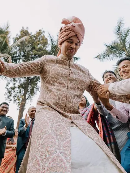 The groom being playfully pulled onto the dance floor by his family. These are the energetic, candid moments that show the joy of the celebration.