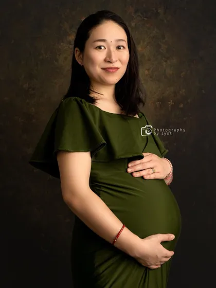 A simple and beautiful close-up portrait against a textured brown background, capturing the radiant glow of the mom-to-be.