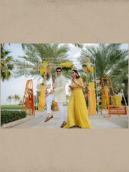 A candid, playful moment from a Mehendi function, framed by a rustic paper-like border for an artistic touch.