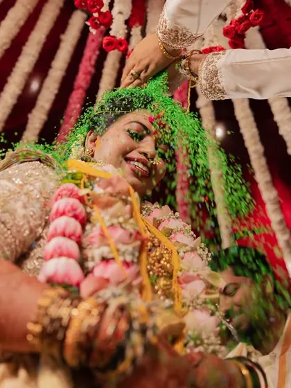 A fun and colorful moment from a wedding ritual, where the couple is showered with green colored rice.