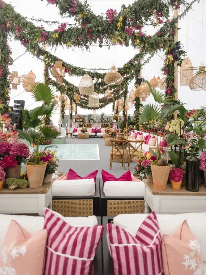 The English countryside Mehendi, filled with lush, colorful florals, comfortable lounge seating with bright pink cushions, and charming wicker details.