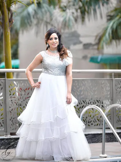 A full-length portrait of the bride-to-be in a stunning white tiered gown for her engagement. She stands by the pool, posing with confidence and grace.