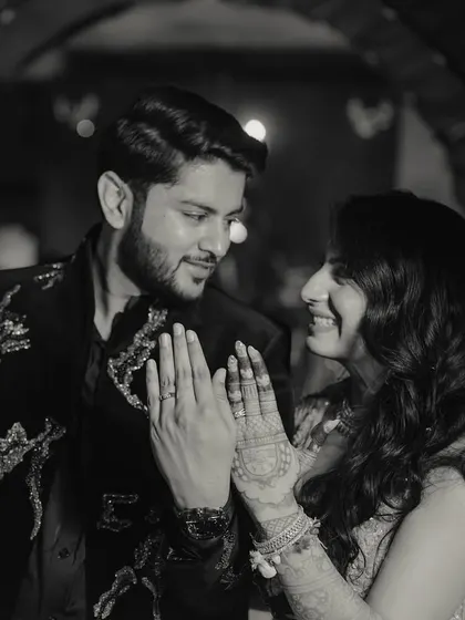 A classic black and white portrait showing the bride's intricate henna and the couple's happy smiles after their engagement.
