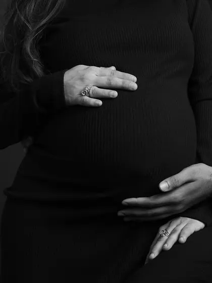A close-up on the hands and the bump. This simple, focused black and white shot tells a powerful story of connection and anticipation.