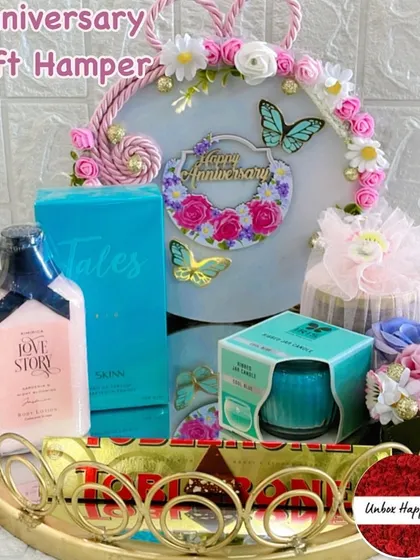 A curated anniversary gift set with 'Love Story' lotion, a 'Skinn' perfume by Titan, a scented candle, and Toblerone chocolate.