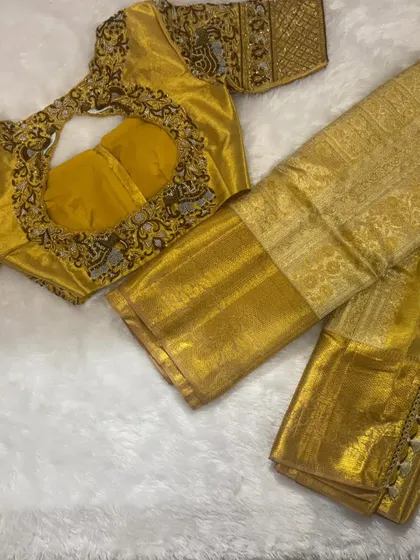 A complete Muhurtham look. A divine gold silk saree paired with a heavily hand-embroidered blouse featuring elephant motifs.