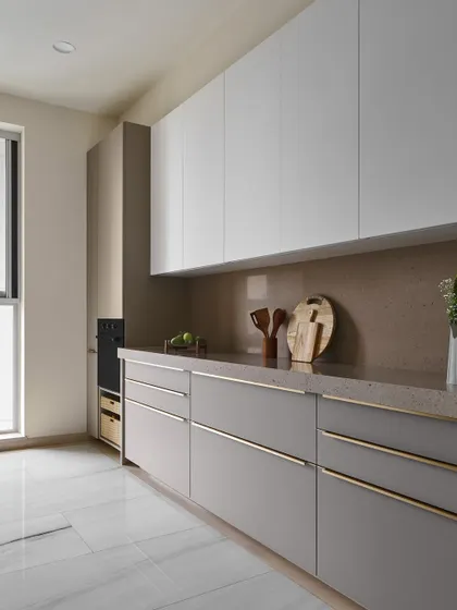 This angle of the kitchen showcases the full expanse of handle-less upper cabinets and sleek lower drawers. The design prioritizes functionality and a clutter-free look, with ample light from the large window.