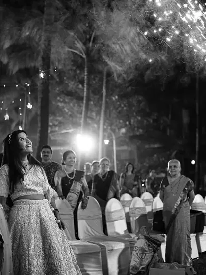 A dramatic black and white shot of the couple's entrance, with a cold pyro sparkler lighting up the night and the admiring faces of their guests.
