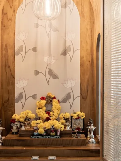 A serene pooja unit designed with natural wood and elegant rattan doors. The arched niche and lotus-patterned wallpaper create a peaceful and sacred space, beautifully integrating traditional elements into a modern home.