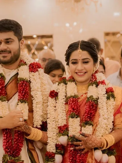 The newlyweds walk together after the ceremony, their faces beaming with happiness, adorned with beautiful garlands.