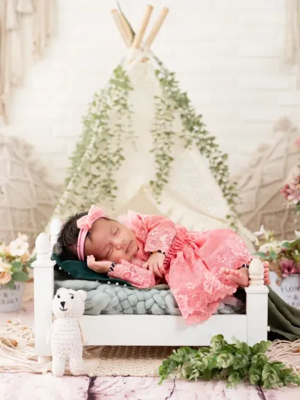 A wider shot of the baby in the pink dress, showing the full boho-tent setup in the background.