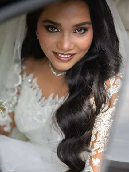 A stunning close-up of the bride, her eyes and smile radiating happiness as she sits in the wedding car.