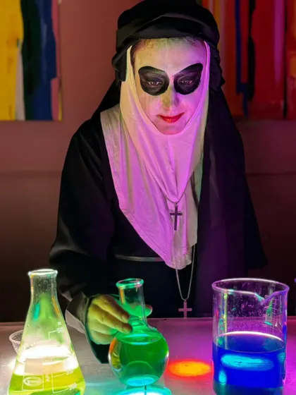 The spooky nun character carefully mixes colorful glowing liquids during the Halloween science workshop, creating a captivating show.